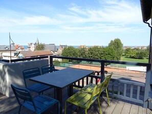 A balcony with a table and chairs, overlooking a tennis court and residential buildings. - L'Horizon, duplex with terrace, sea vue (Hautot-sur-Mer)