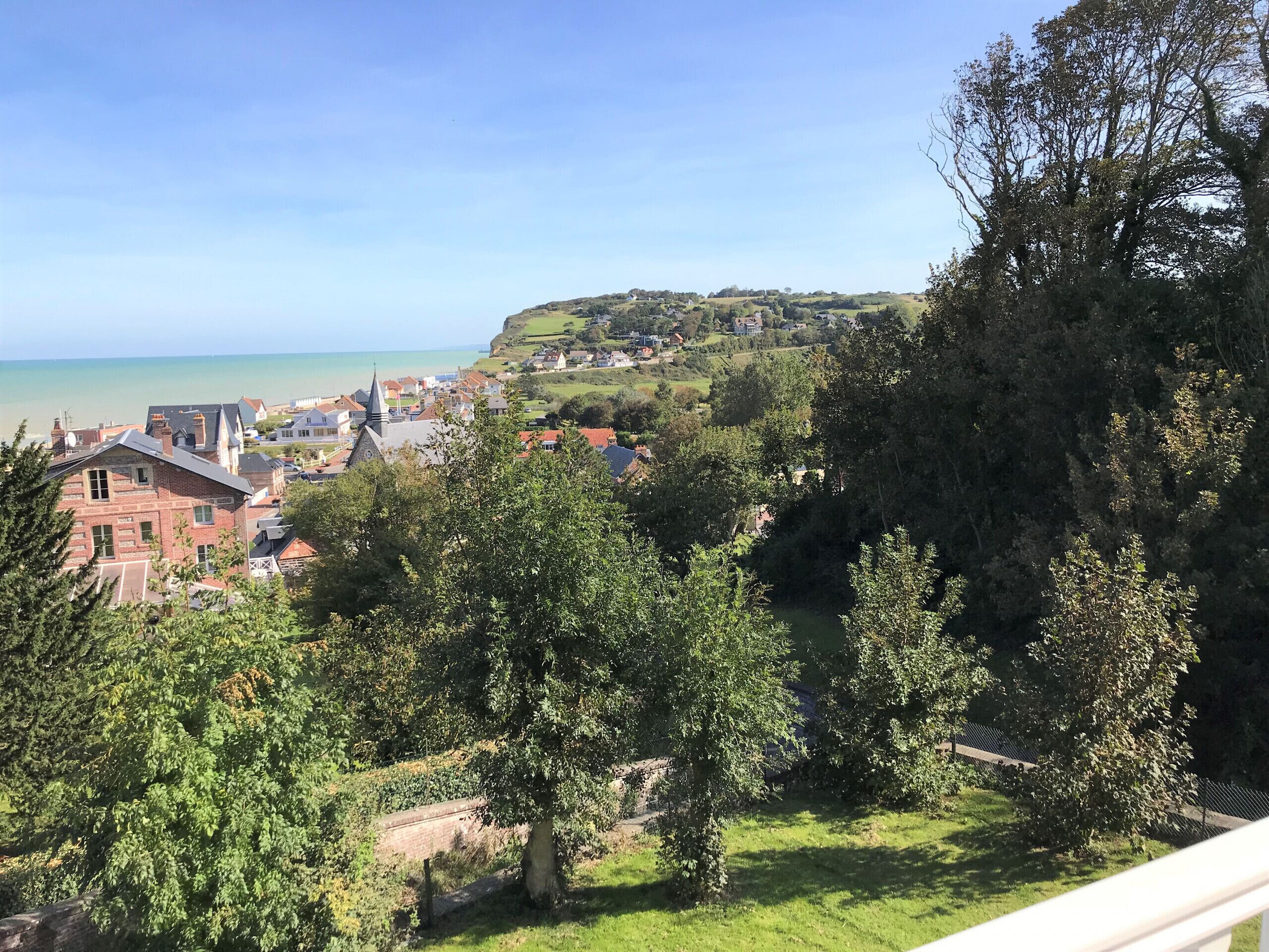 A coastal town with a prominent church, lush greenery, and a view of the sea.