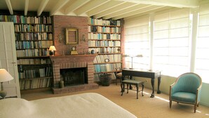 Une pièce avec une cheminée, des étagères à livres, un bureau, une chaise et un lit.