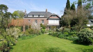 Une grande maison en briques, dotée d’une pelouse et d’un jardin bien entretenus.