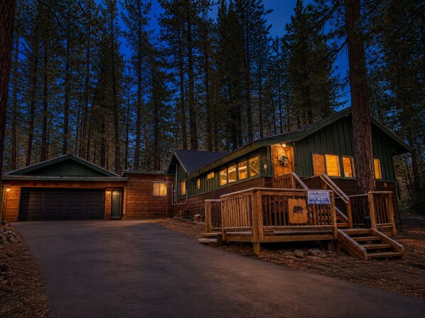 A cabin with a covered porch, a garage, and a deck.