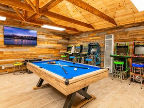 A pool table in a wooden room with arcade games and a TV mounted on the wall. - Evergreen Paradise - Hot Tub, Game Room, Pool Table, Foosball (Big Bear Lake)