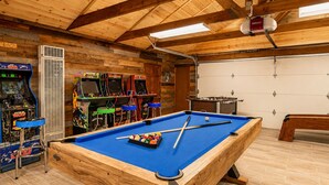 Un tavolo da biliardo circondato da giochi arcade e un tavolo da calcio in una sala in legno.