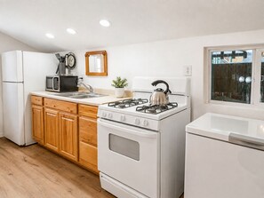 A modern kitchen with white appliances, wooden cabinets, a gas stove, and a microwave. - Evergreen Paradise - Hot Tub, Game Room, Pool Table, Foosball (Big Bear Lake)