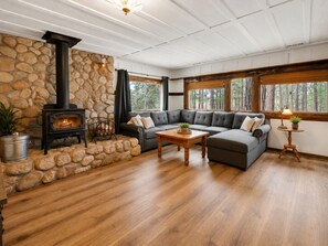 Una sala de estar acogedora con pared de piedra, chimenea, sofá modular y suelo de madera.