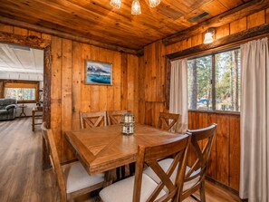 A wooden interior with a dining table, chairs, and a painting on the wall. - Evergreen Paradise - Hot Tub, Game Room, Pool Table, Foosball (Big Bear Lake)