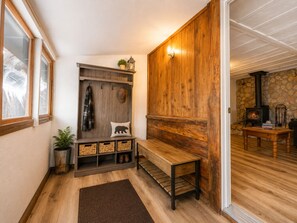 Un interior de madera con un banco, un estante de pared con cestas y una pared de piedra con chimenea.