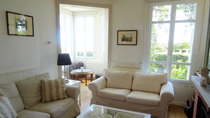 A living room with two sofas, a glass coffee table, a lamp, a chair, and a fireplace. - Consolata (Hautot-sur-Mer)