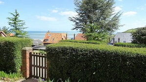 A coastal property with a view of the sea, featuring a well-maintained hedge, a wooden gate, and a tiled roof house. - Consolata (Hautot-sur-Mer)