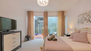 A hotel room with a bed, a TV, a dresser, and a view of the outside. - Modern villa El Duque with pool (Costa Adeje)