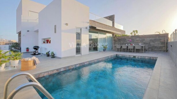 A modern villa with a swimming pool, outdoor seating, and a stone wall. - Modern villa El Duque with pool (Costa Adeje)
