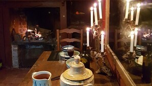Una mesa de comedor dispuesta con tetera, tazas y vasos, rodeada de velas y una chimenea.