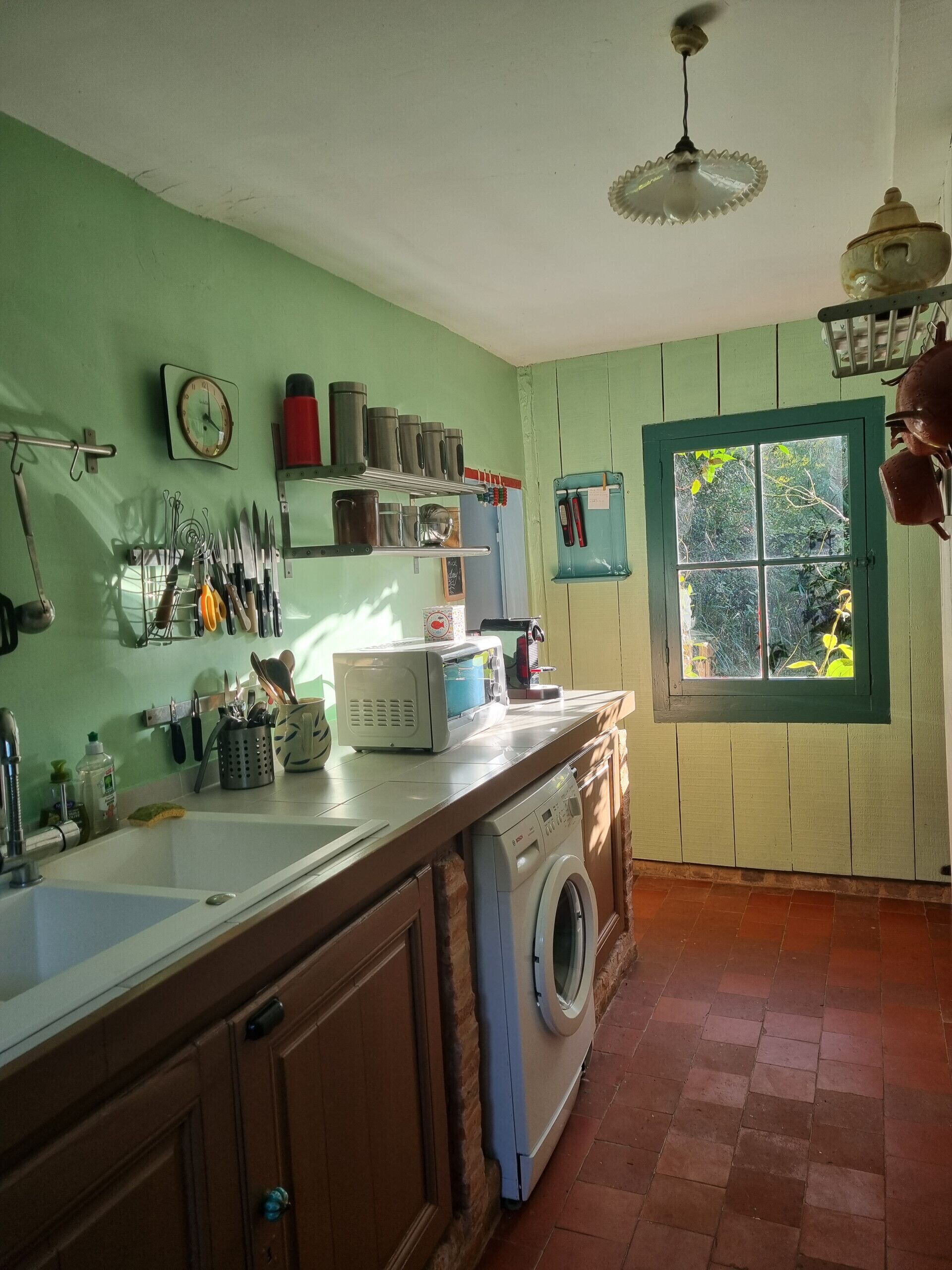 Una cocina con lavadora, un lavamanos y diversos utensilios y electrodomésticos.