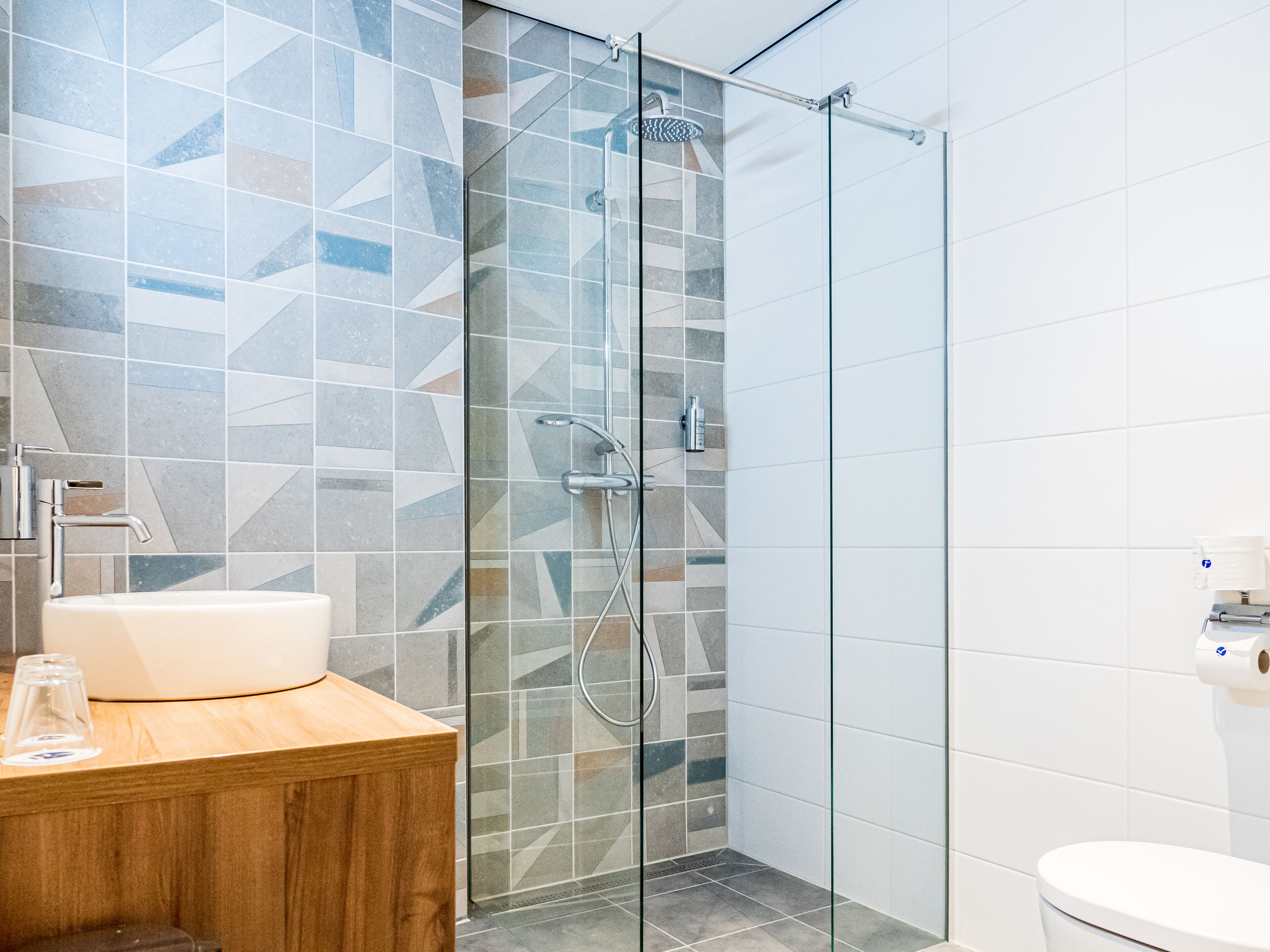 A modern bathroom with a glass-enclosed shower, a wooden vanity with a sink, and a toilet.
