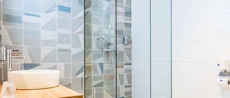 A modern bathroom with a glass-enclosed shower, a wooden vanity with a sink, and a toilet.