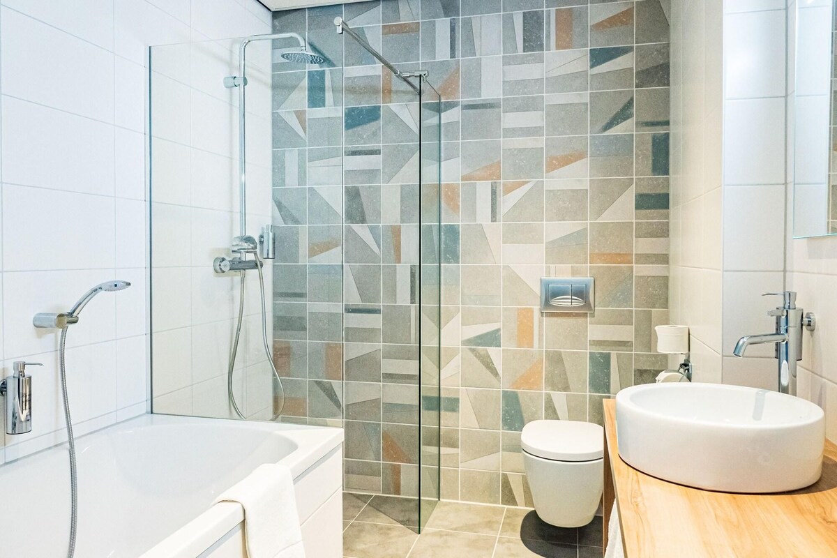Ein modernes Badezimmer mit einer Duschkabine, einer Badewanne und einem Waschbecken.