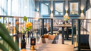 En modern restaurang med högt i tak, stora fönster och en variation av sittgrupper.