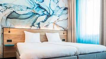 A modern hotel room with a large bed, a wooden headboard, and a marble wall mural.