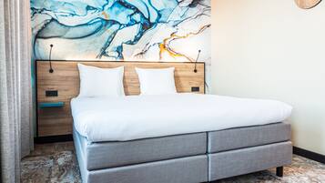 Un dormitorio moderno con una cama grande, cabecera tapizada en gris y suelo estampado con diseño de mármol.