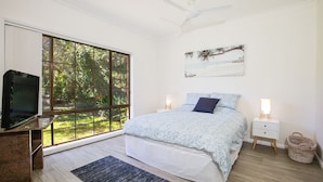 Une chambre avec une grande fenêtre, un lit, une télévision et des lampes de chevet.