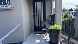 Un espacio al aire libre cubierto con una puerta, una silla, una planta en maceta y un farol.