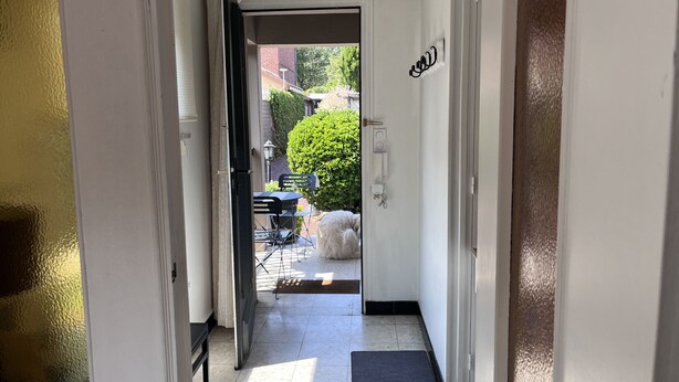 Pasillo que conduce a un espacio exterior con una puerta, una mesita y sillas.
