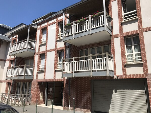 A multi-story apartment building with balconies, a garage, and a gated entrance.