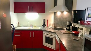 Una cocina con armarios rojos, una estufa blanca y un lavamanos de acero inoxidable.