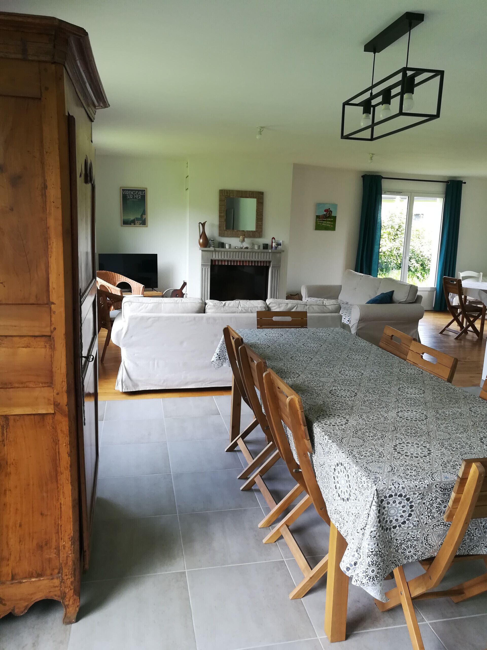 Ein geräumiges Wohnzimmer mit Kamin, einem Esstisch mit Stühlen und einem Fernseher.