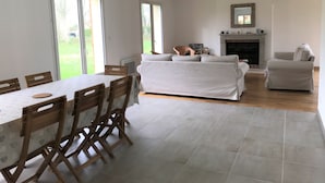 A spacious living area with a dining table, chairs, a sofa, and a fireplace. - Le Cèdre (Varengeville-sur-Mer)