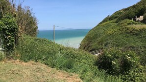 A coastal landscape with a view of the sea, a grassy hill, and dense greenery. - Valleuse (Saint-Léonard)