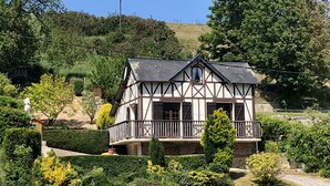 A traditional half-timbered house with a balcony, surrounded by well-maintained gardens and trees. - Valleuse (Saint-Léonard)