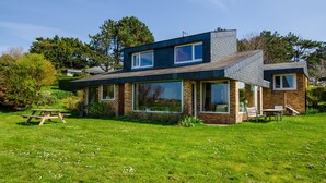 A modern two-story house with large windows, a brick exterior, and a well-maintained lawn.
