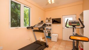 Une salle de sport équipée de tapis de course, d’un téléviseur et d’un petit réfrigérateur.