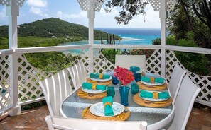 A table set for four with a view of the ocean and hills.