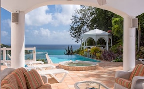 Ein Poolbereich mit Liegestühlen, einem Whirlpool und einem Gazebo mit Blick aufs Meer.