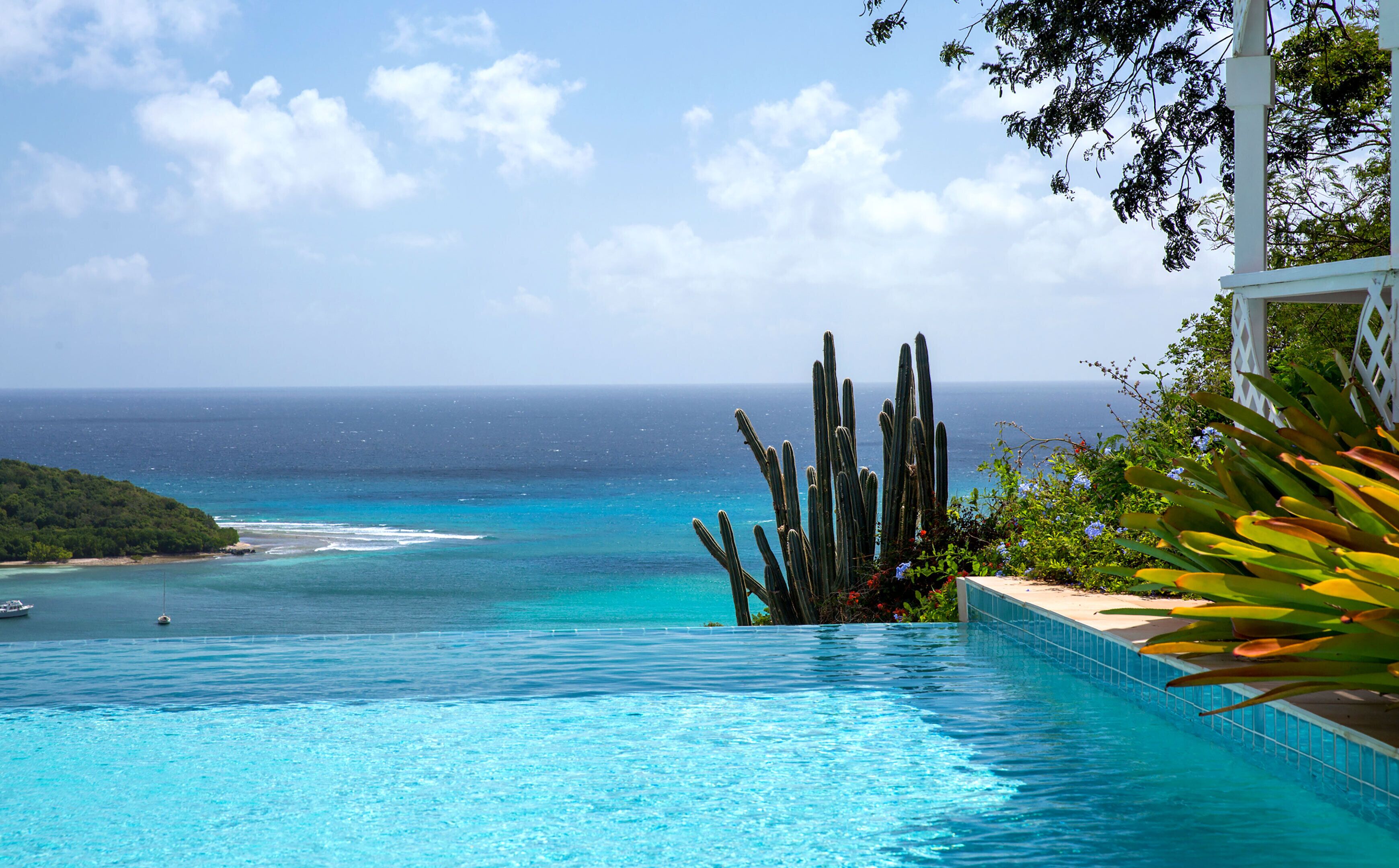 A clear view of a swimming pool with a view of the ocean and a distant beach.