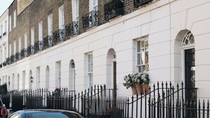 A row of white buildings with black iron railings and windows.