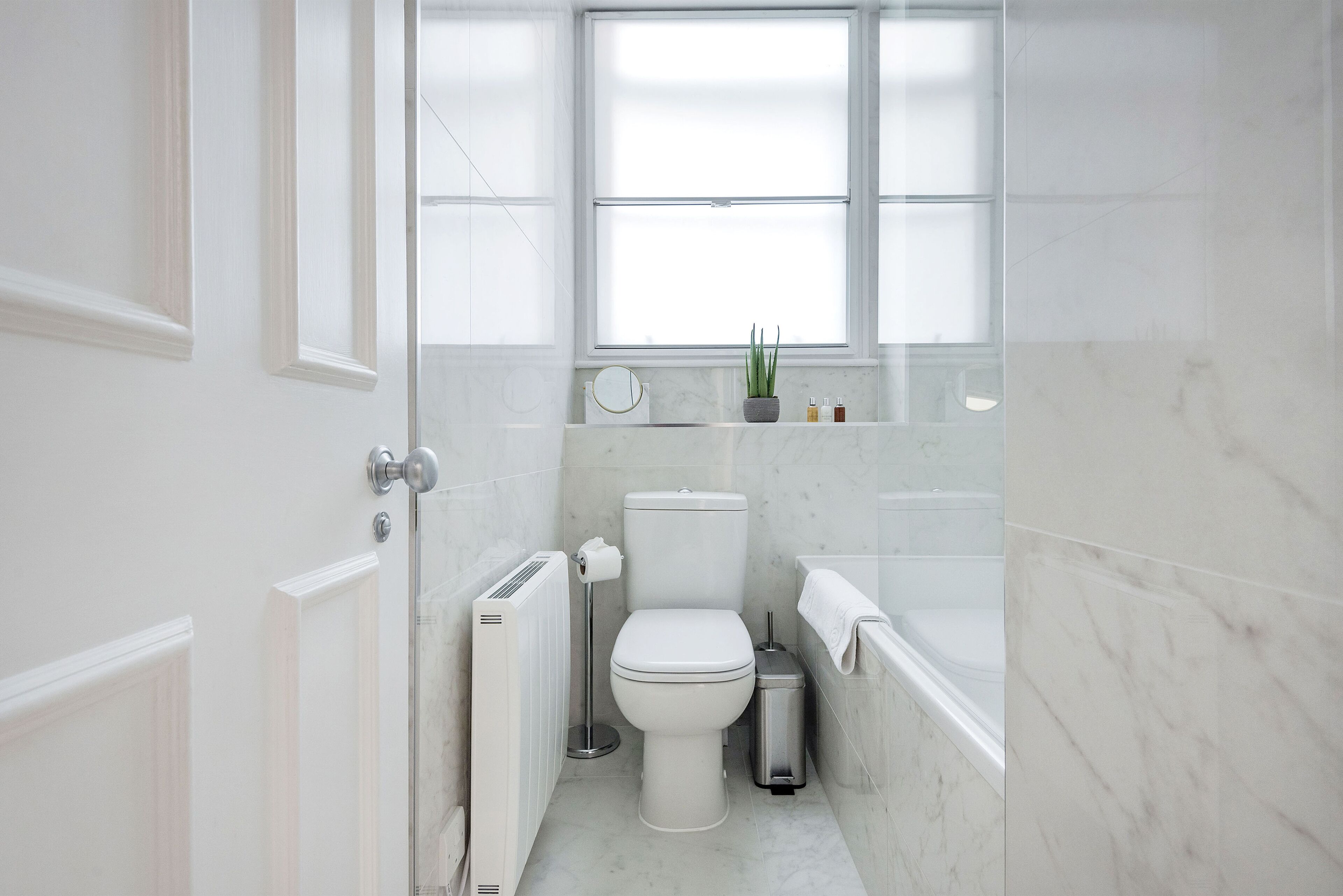 A modern bathroom with a toilet, bidet, and a small window above the sink.