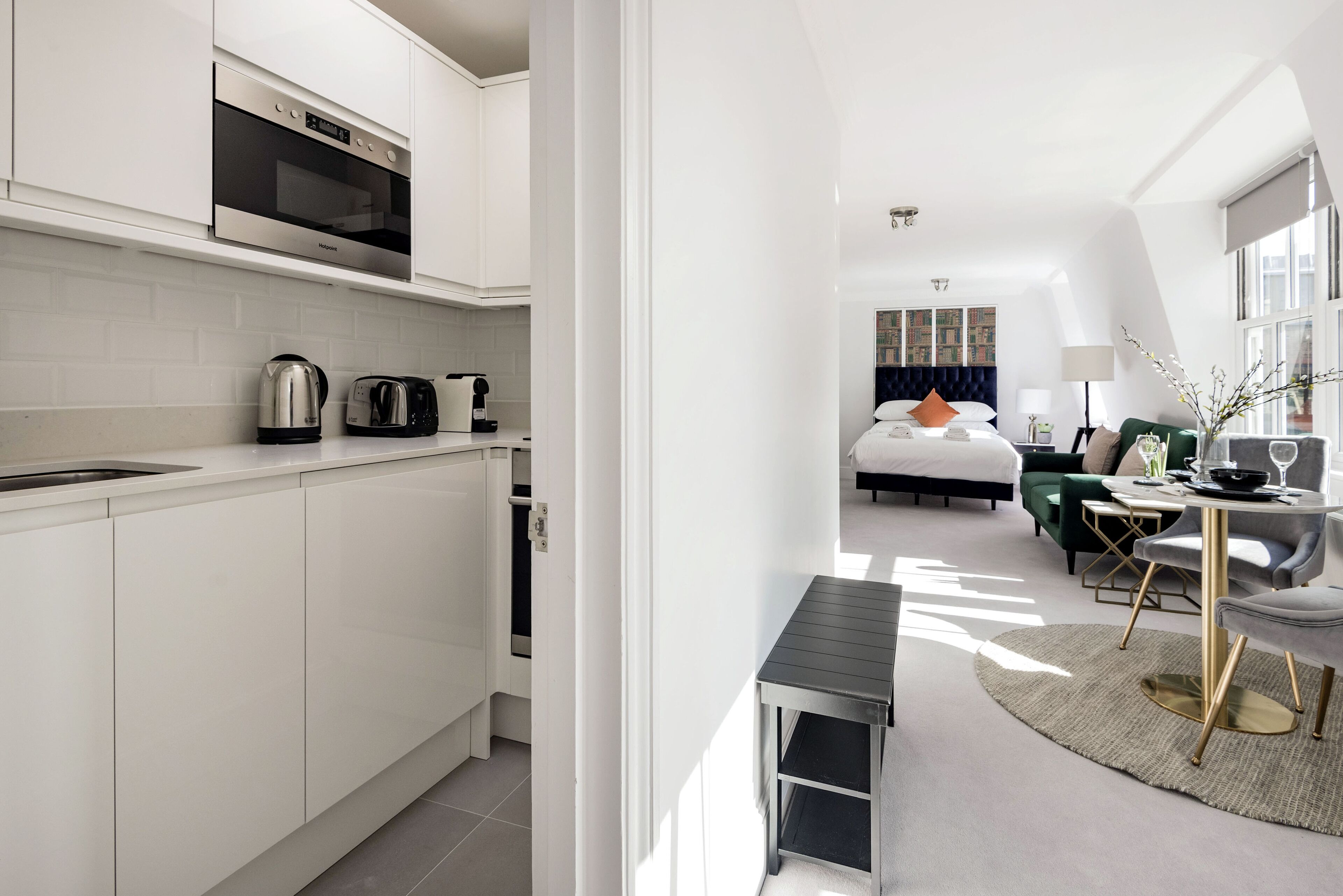 A modern kitchen with white cabinets, a built-in oven, and a coffee machine.