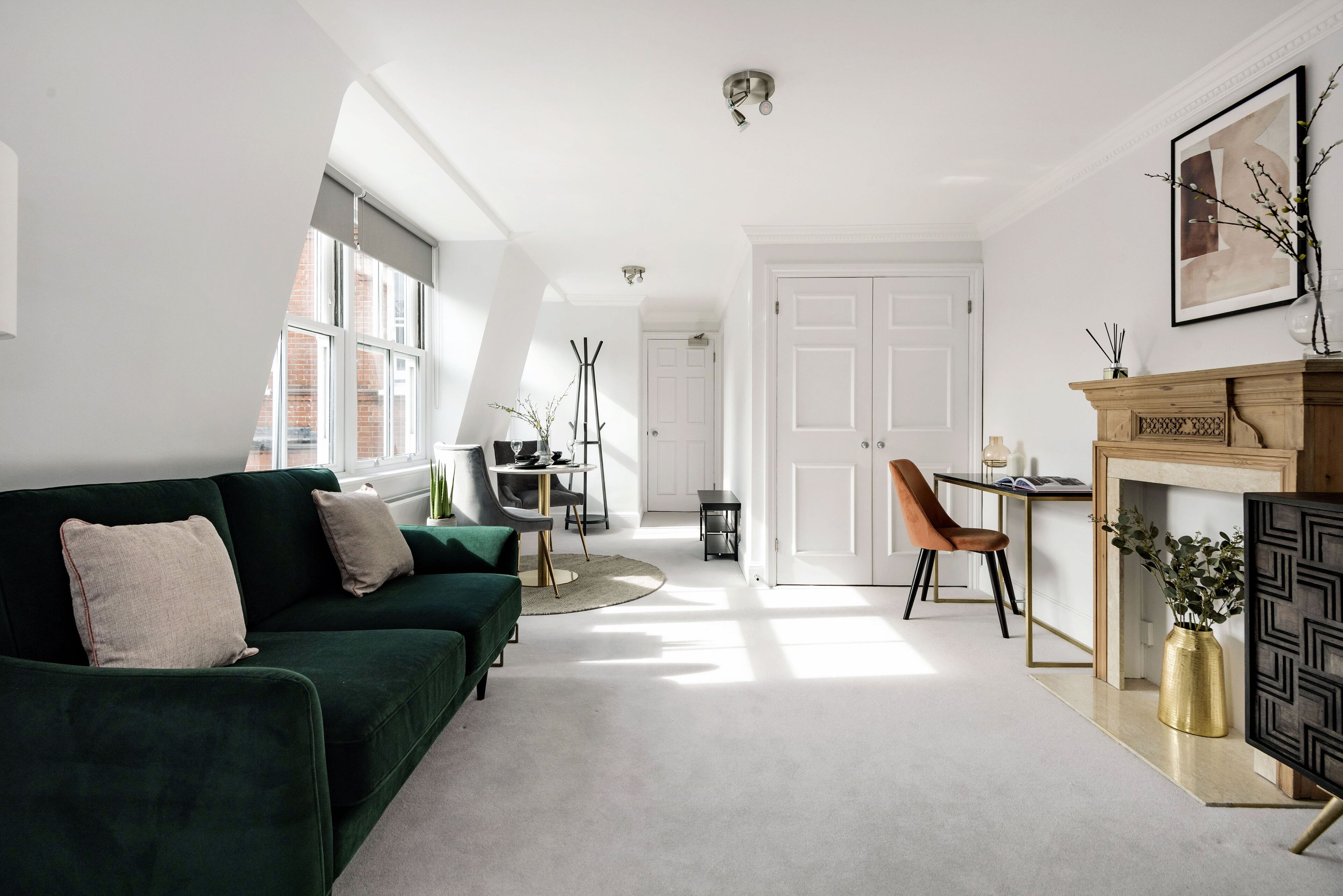 A modern living room with a green sofa, a fireplace, and a dining area with a table and chairs.