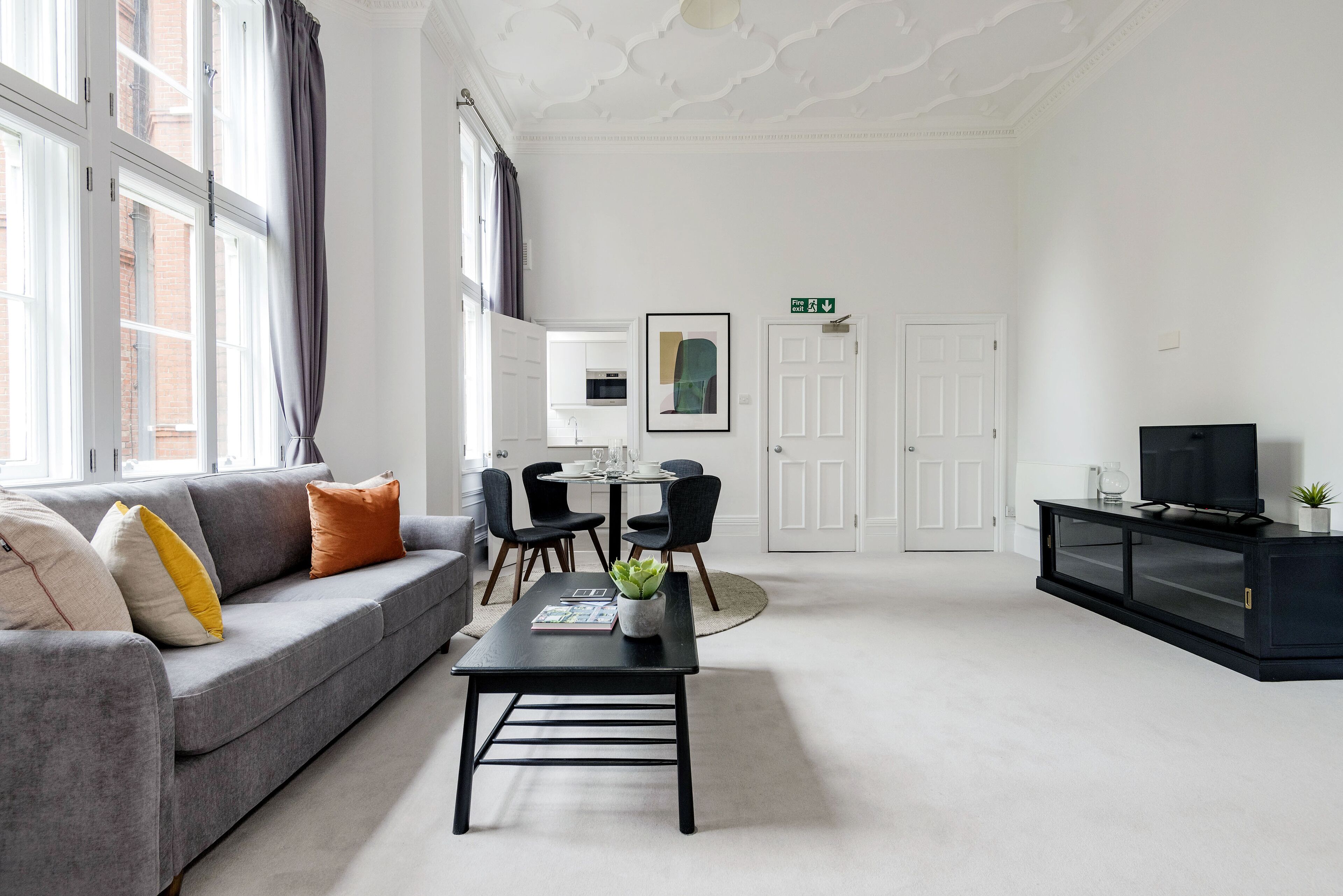 A modern living room with a grey sofa, a black coffee table, and a TV on a black cabinet.