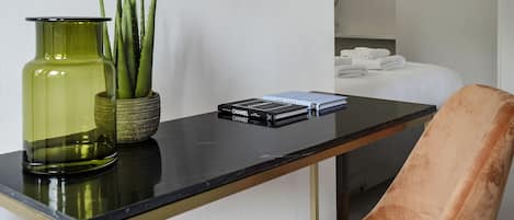 A modern room with a black glass table, a green vase with plants, and a plush brown chair.