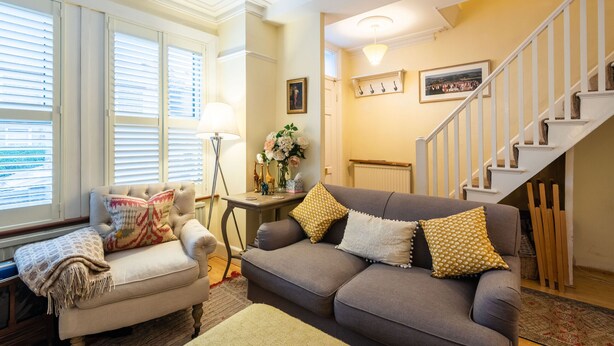 Un salon avec un canapé, un fauteuil et un escalier.