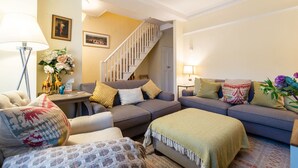 Un salon confortable avec un canapé, des fauteuils, une table basse et un escalier.