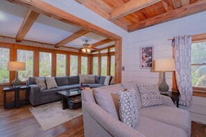 A cozy living room with wooden beams, a sofa set, a coffee table, and a fireplace.