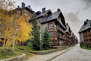 A multi-story building with a stone facade, wooden balconies, and a cobblestone pathway.