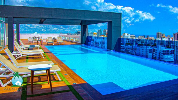 Una piscina en la azotea con sillas de descanso y vistas a la ciudad.