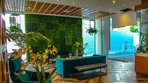 Un interior moderno con una pared verde, zona de estar y suelo de madera.