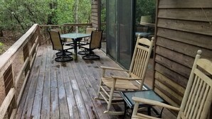 En træterrasse med en glasdør, der fører ud til en patio med et bord og stole.